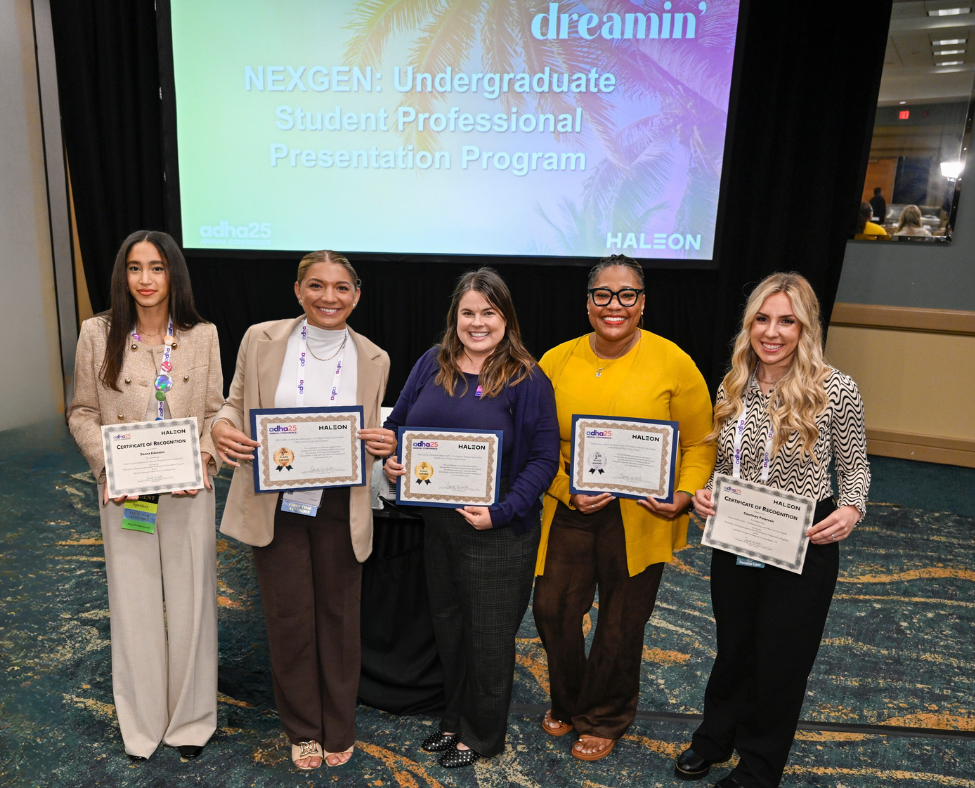 5 Hygiene Students in business attire stand in front of presentation screen holding award certificates