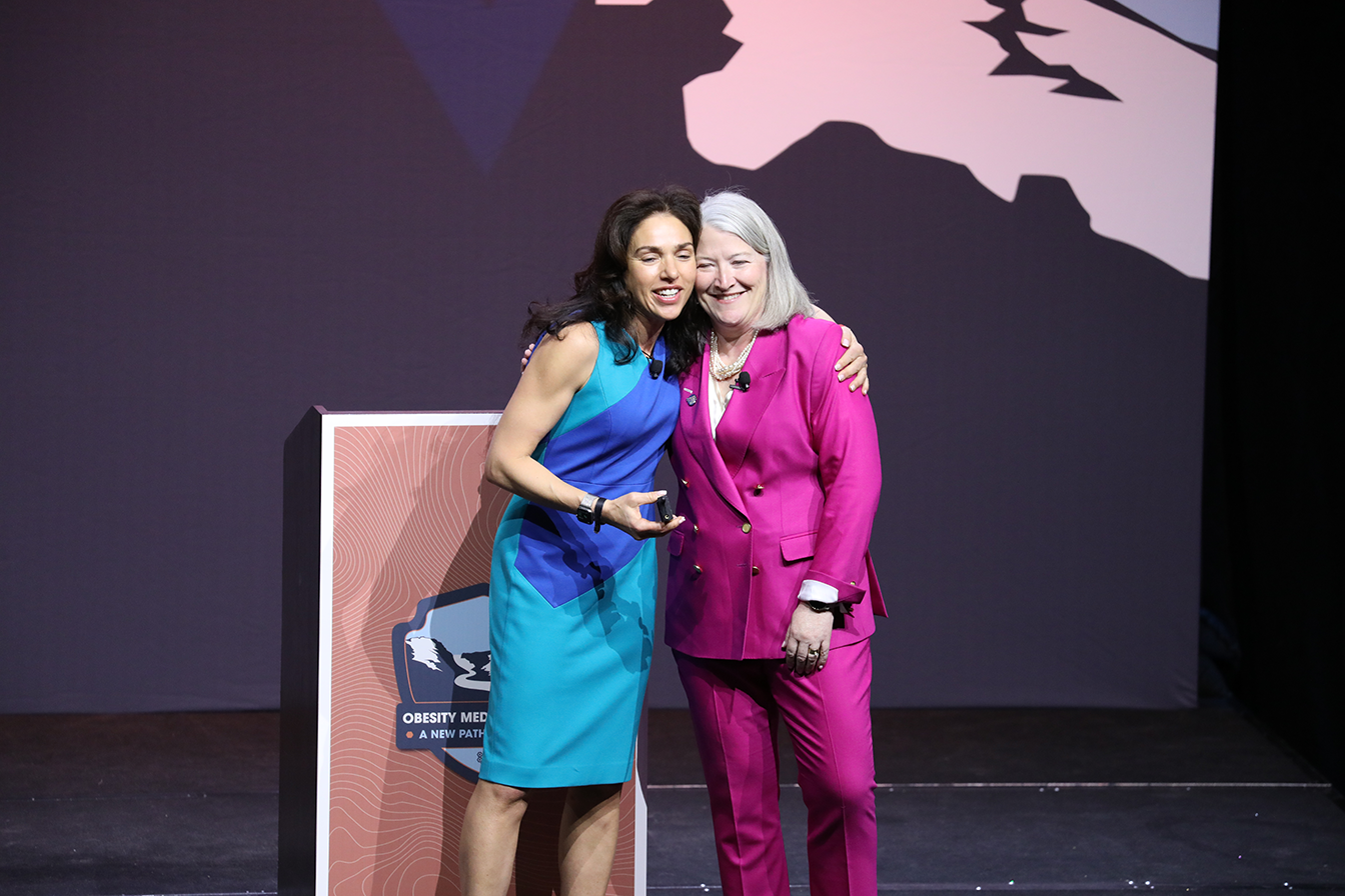 two women hugging on a stage